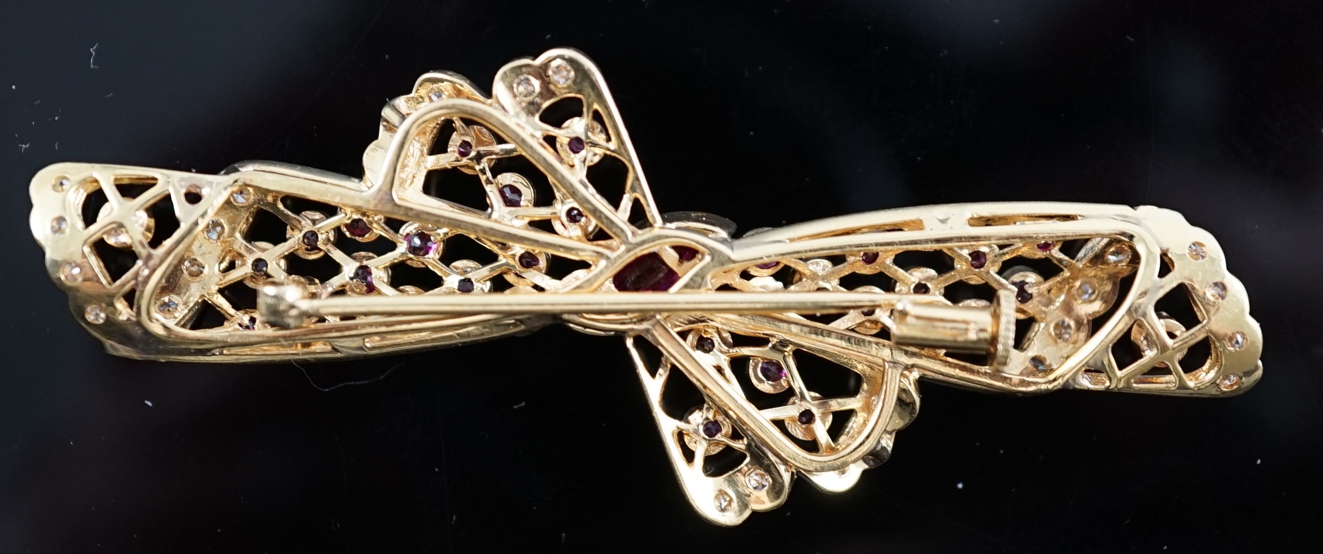 A mid to late 20th century pierced 18ct gold, ruby and diamond set ribbon bow brooch